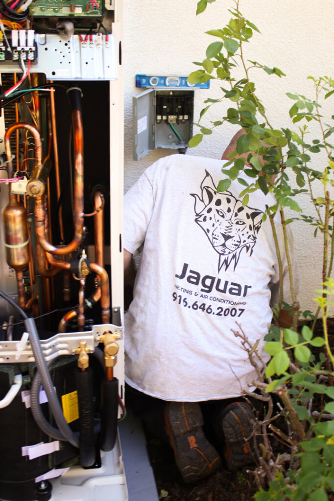 An HVAC technician servicing an outdoor HVAC unit for Jaguar Heating & Air in Sacramento, CA