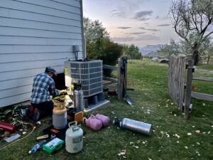An HVAC technician from Just Heat Pumps performs maintenance on an outdoor heat pump unit in Denver, CO.