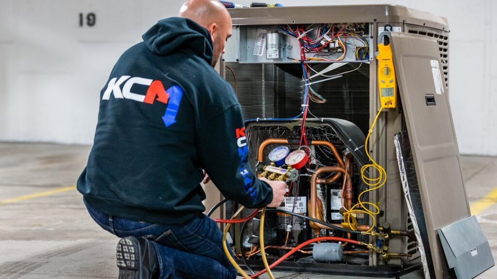 An HVAC technician from KCM Heating & Air Conditioning servicing an outdoor unit in Omaha, NE.