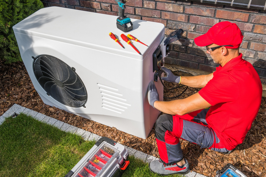 An HVAC technician servicing an outdoor heat pump unit for McIntosh Heating & Cooling in Independence, MO.