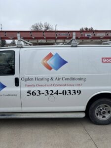 An HVAC technician servicing an outdoor air conditioning unit for Ogden Air Conditioning & Heating in Davenport, IA.