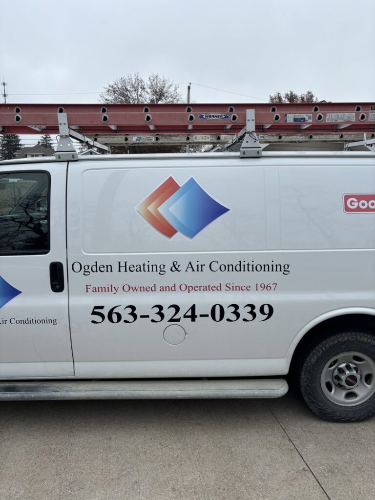 An HVAC technician servicing an outdoor air conditioning unit for Ogden Air Conditioning & Heating in Davenport, IA.