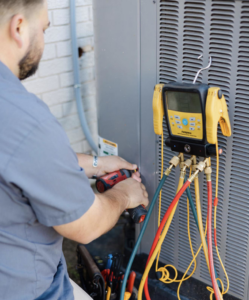 An HVAC technician servicing an outdoor air conditioning unit with gauges at Target Temp, LLC in Houma, LA.