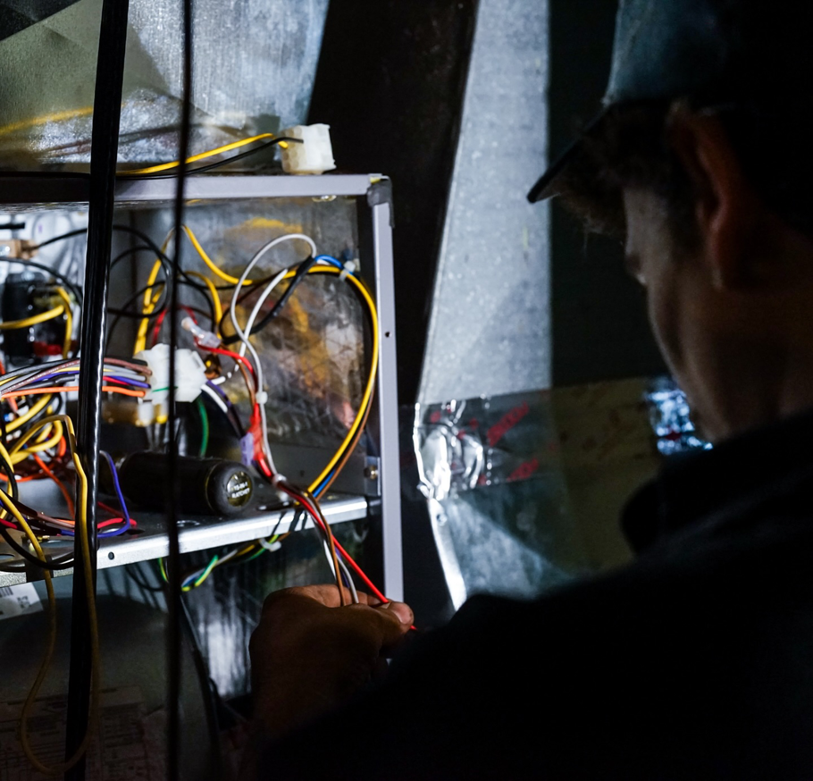 An HVAC technician from Triple-O servicing an outdoor air conditioning unit in Bergen, NY.