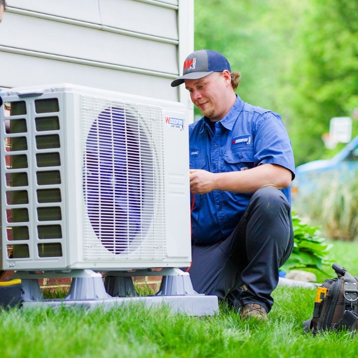 An HVAC technician from Woodfin-Your Home Team servicing an outdoor air conditioning unit in Richmond, VA.