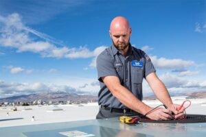 An HVAC technician servicing a rooftop air conditioning unit for Paul's Heating & Air Conditioning in Virginia Beach, VA.