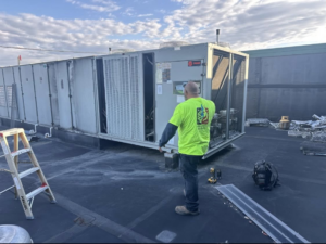 An HVAC technician servicing a large commercial rooftop system for Air Conditioning Experts in Orlando, FL.