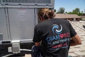 An HVAC technician servicing a rooftop HVAC system for Diamond AC and Heating in Phoenix, AZ.
