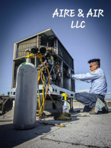 An Aire & Air Heating and Cooling LLC technician servicing a rooftop HVAC unit with gauges in Las Vegas, NV.