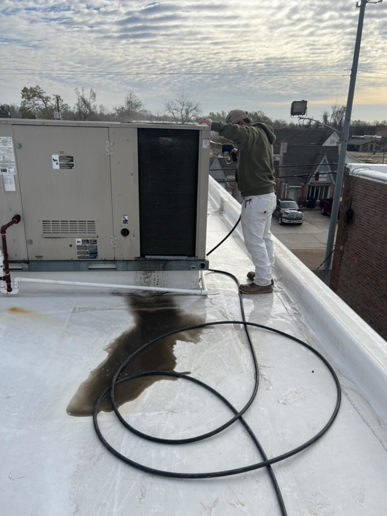 An HVAC technician servicing a commercial rooftop unit for Dent Turner Air Conditioning Sales in Vaiden, MS.