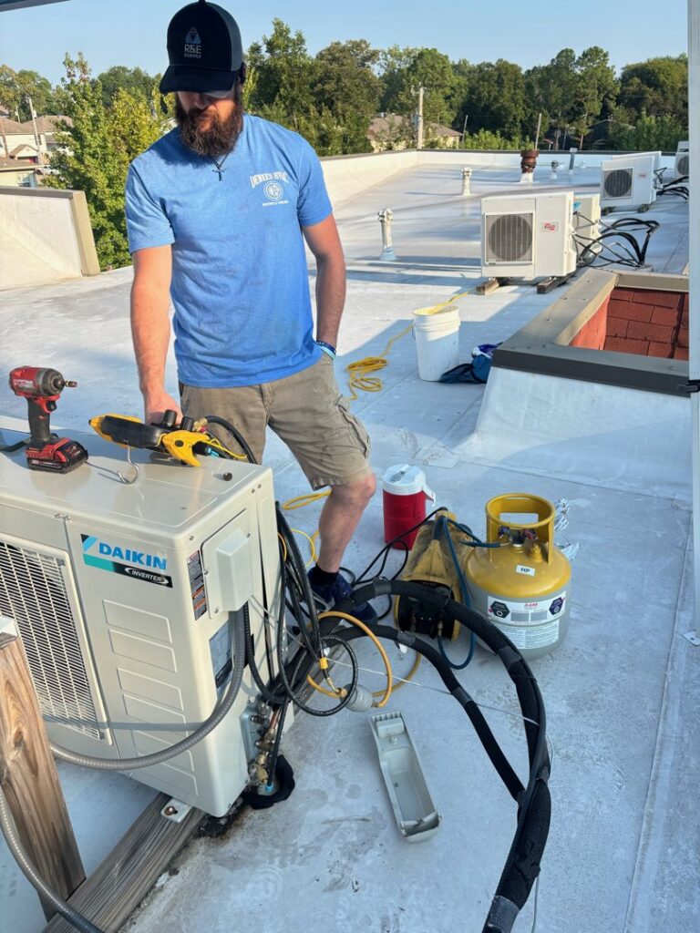 An HVAC technician servicing a Daikin rooftop unit with tools and equipment for Dewees HVAC in Conway, AR.