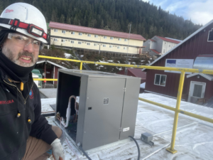 An HVAC technician from Kusi.aat' Kaa' Refrigeration servicing a commercial rooftop unit on a snowy roof in Homer, AK.