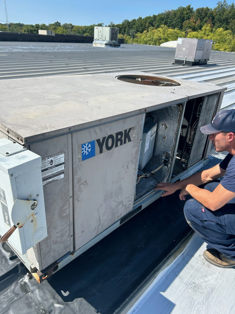 An HVAC technician servicing a commercial rooftop unit for Variable Comfort Solutions in Huntington, WV.