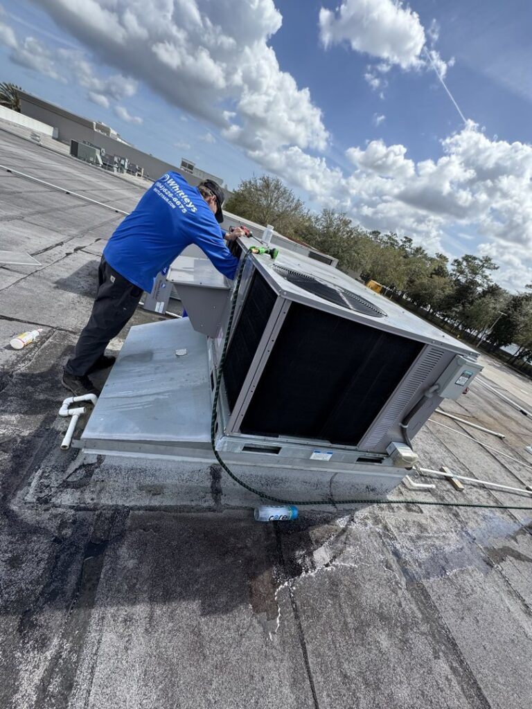 An HVAC technician servicing a commercial rooftop air conditioning unit for Whitleys Heating and Air in Jacksonville, FL.