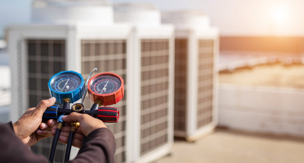 An HVAC technician servicing rooftop units with manifold gauges for Reed's Heating & Cooling in Toms River, NJ.