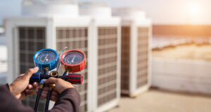 An HVAC technician servicing rooftop units with manifold gauges for Reed's Heating & Cooling in Toms River, NJ.