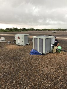 A Tek-Aire Services Inc. technician servicing rooftop HVAC units on a commercial building in Columbia, SC.