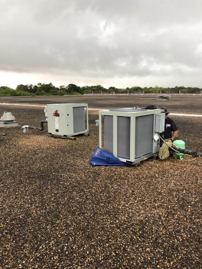 A Tek-Aire Services Inc. technician servicing rooftop HVAC units on a commercial building in Columbia, SC.