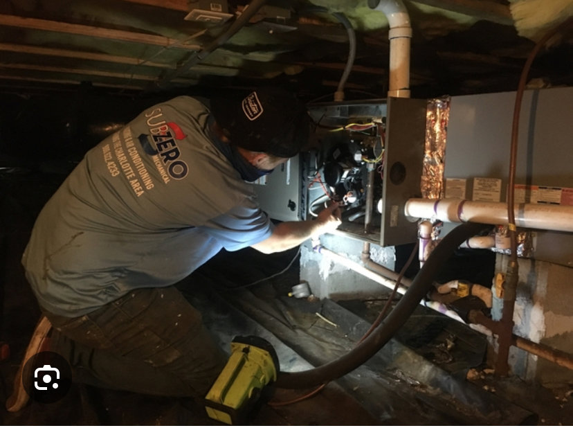 An HVAC technician from Subzero Mechanical LLC Heating & Air servicing an indoor unit in Concord, NC.