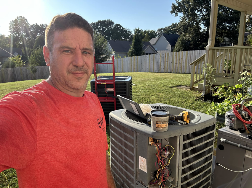 An HVAC technician servicing outdoor condenser units in a backyard for Eaton Companies LLC in Clarksville, TN.