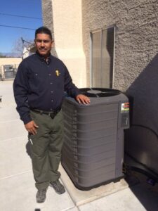 An HVAC technician standing proudly by a newly installed outdoor AC unit from AC Plus Heating & Air Conditioning Service in Las Vegas, NV.