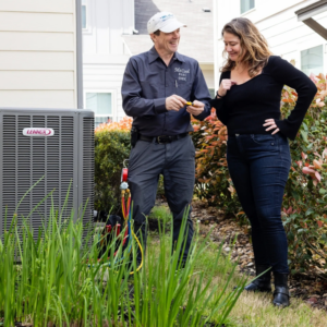 An HVAC technician from Mr. Cool HVAC talking to a customer next to an outdoor Lennox unit in Cypress, TX.