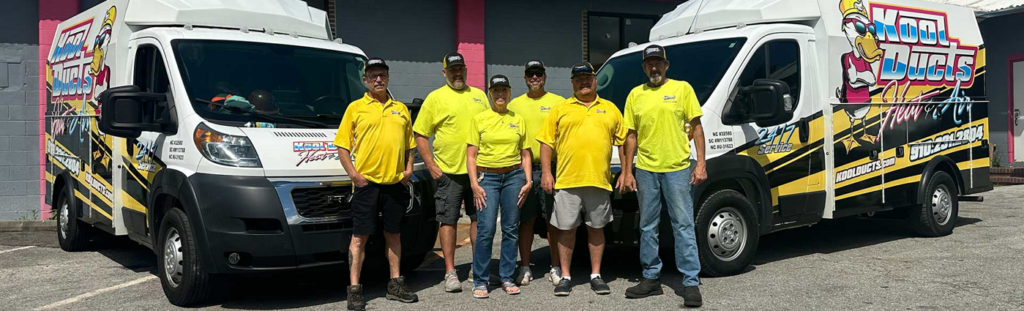 The professional HVAC technician team from Kool Ducts Heat & Air standing with their service vans in Wilmington, NC.