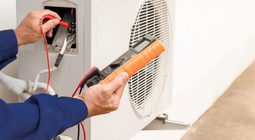 An HVAC technician using a multimeter to test an outdoor air conditioning unit for Varsity Zone HVAC of Fishers, IN.