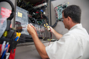 An HVAC technician using a multimeter to test electrical components in a control panel for Climate Systems, Inc. in Sioux Falls, SD.