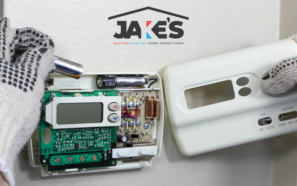 An HVAC technician working on the internal components of a thermostat for Jake's Heating and Cooling in Buffalo, NY.