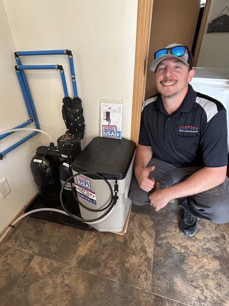 A Comfort Heating, Cooling & Electrical technician giving a thumbs up next to an outdoor AC unit in Post Falls, ID