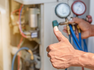 An HVAC technician giving a thumbs up while holding refrigerant gauges, performing service for Trenary Service Company in Martinsburg, WV.