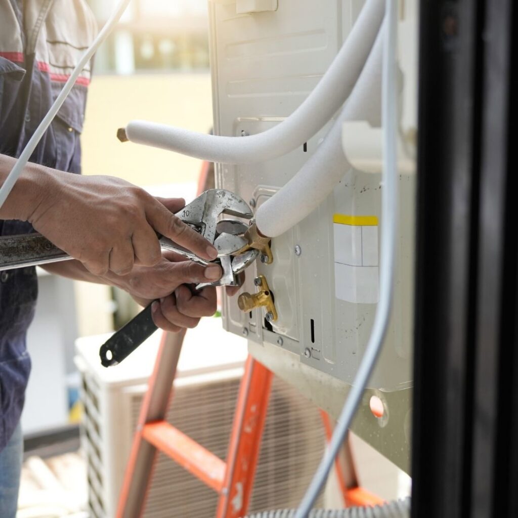 An HVAC technician tightening a refrigerant line connection on an outdoor AC unit at Integrity Airworks in Hoover, AL.