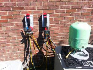 HVAC technician tools, including manifold gauges and a refrigerant tank, connected to an outdoor unit by Madison HVAC/R, Inc in Richmond, KY.