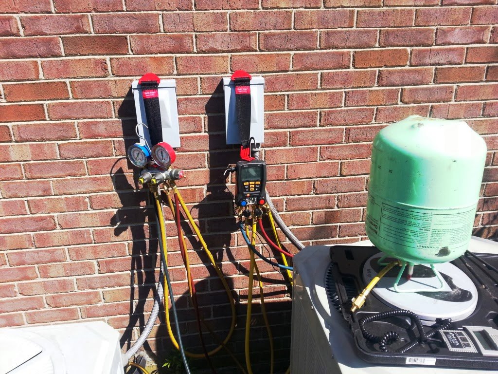 HVAC technician tools, including manifold gauges and a refrigerant tank, connected to an outdoor unit by Madison HVAC/R, Inc in Richmond, KY.