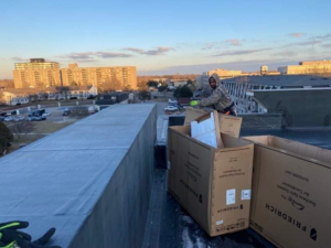 An HVAC technician unboxing Friedrich ductless split system air conditioner units on a rooftop for Embassy Heating and Air Conditioning in Toledo, OH