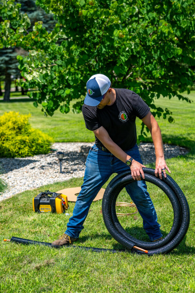An HVAC technician from Comfort Craftsman Heating & Cooling unrolling insulated refrigerant lines for an installation in Westland, MI.