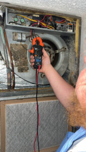 An HVAC technician using a clamp meter to measure electrical current on an HVAC unit by Direct Service HVAC & Maintenance in Lewisburg, OH.