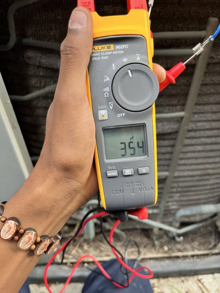 An HVAC technician using a Fluke HVAC clamp meter to diagnose an outdoor unit at Keith HVAC & Electrical Enterprises LLC in New Orleans, LA.