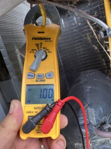 An HVAC technician using a clamp meter to check electrical readings on an AC unit for Texas Air & Heat in Arlington, TX.