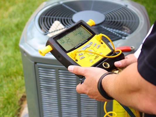 An HVAC technician using a digital manifold gauge to service an outdoor unit for Air Works of Alabama LLC in Mobile, AL.