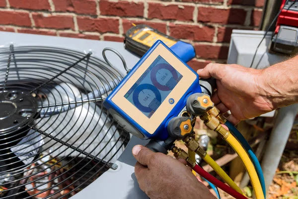 An HVAC technician using a digital manifold gauge to check an air conditioning unit for Boykin Air Conditioning Services in Sumter, SC.