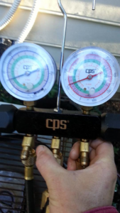 An HVAC technician using manifold gauges to check refrigerant levels for Air Vent Master in Charlotte, NC.