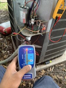 An HVAC technician using a megohmmeter to test an outdoor HVAC unit at Keith HVAC & Electrical Enterprises LLC in New Orleans, LA.