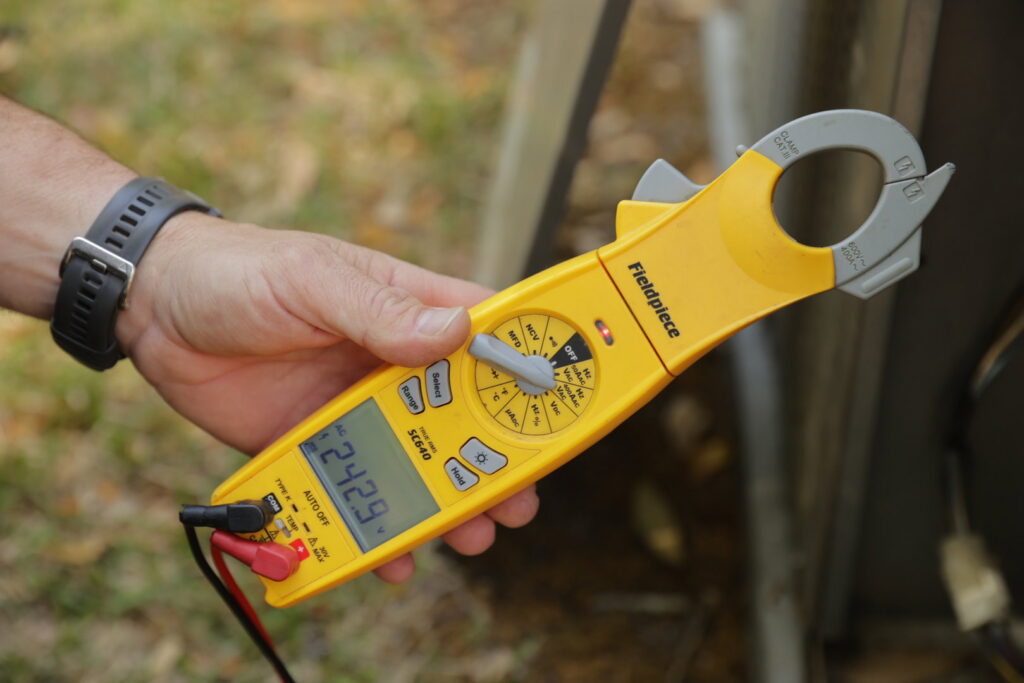 An HVAC technician using a multimeter to diagnose an HVAC system for 5 Star Charleston Heating and Air in Charleston, SC.