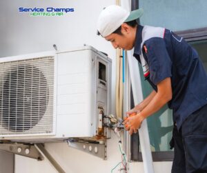 An HVAC technician servicing a wall-mounted outdoor air conditioning unit for Service Champs Heating and Air in Fort Worth, TX.