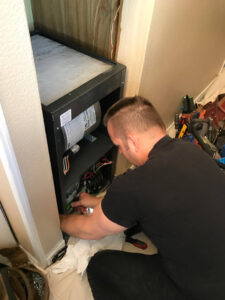 An HVAC technician from Columbia Heating & Air Conditioning wiring an indoor furnace unit in Kent, WA.