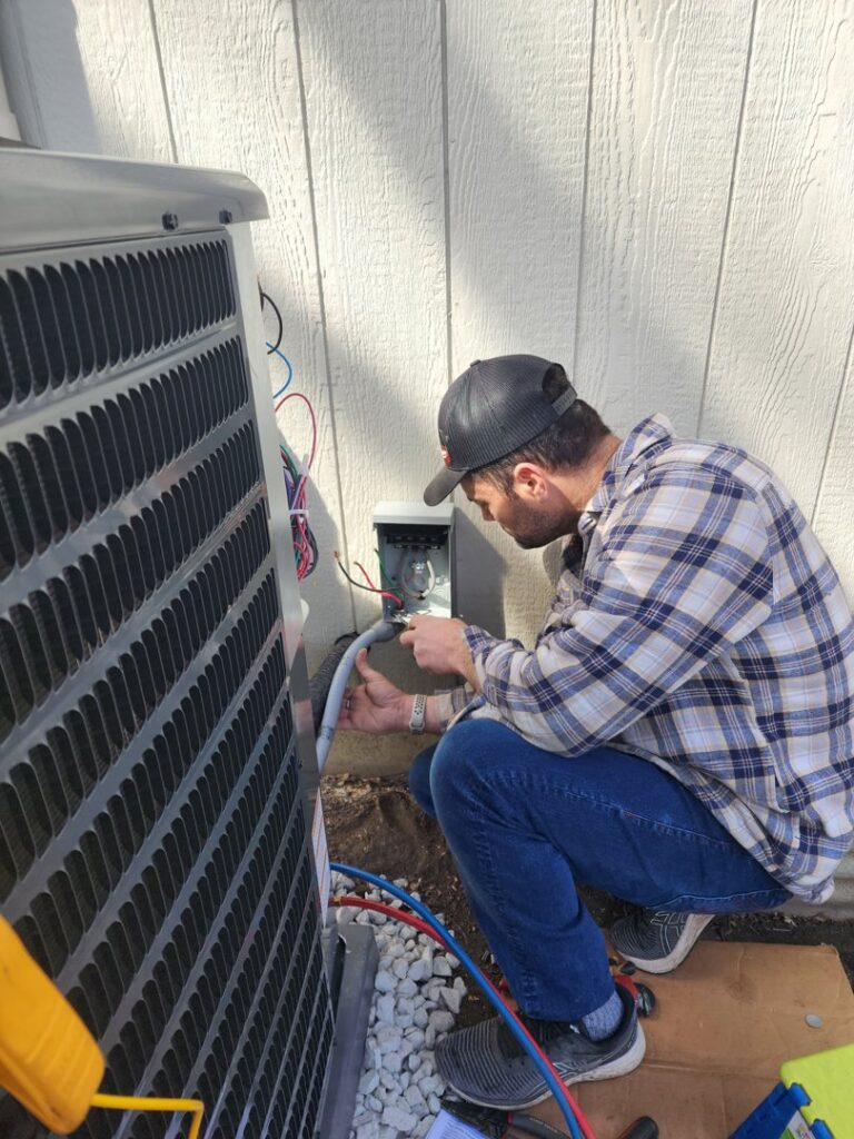An HVAC technician connecting electrical wiring to an outdoor air conditioning unit for Dad's Heating and Cooling in Blue Springs, MO.