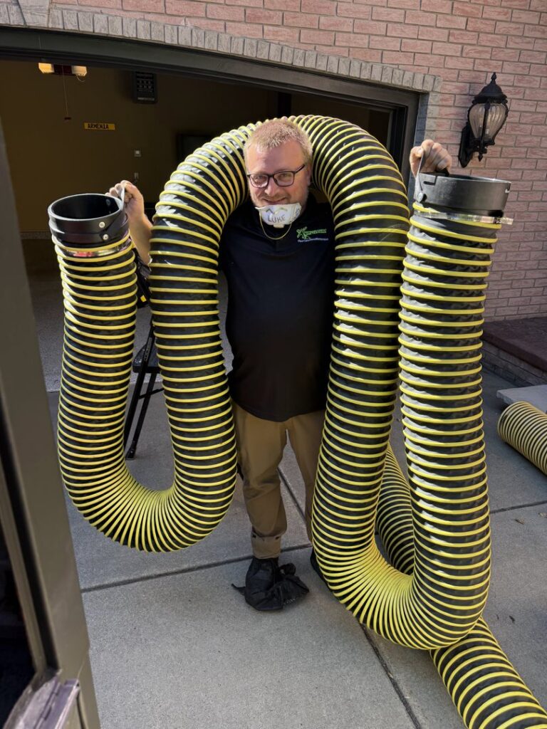 An HVAC technician holding large flexible air duct hoses for a job by Extreme Carpet And Tile Clean in Alden, NY