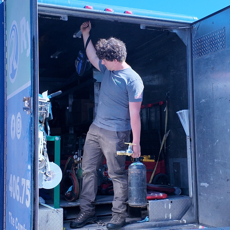 A Ryan's Heating & Air technician with a gas cylinder and tools in a service truck in Kalispell, MT.
